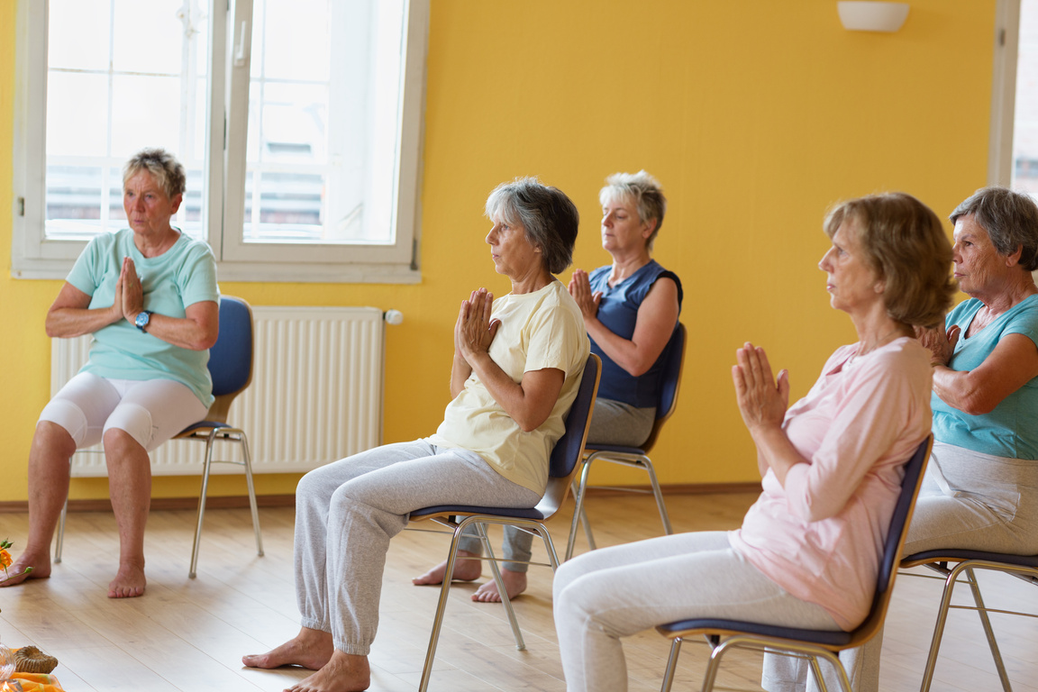 active senior women in yoga class exercisig on chairs